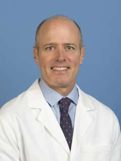 Head shot of S. Thomas Carmichael in a white lab coat, smiling at the viewer