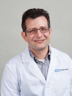 Portrait of Carlos Lerner in a lab coat against a neutral background.