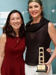 Jeannine Walston with colleague smiling, one woman holding a trophy