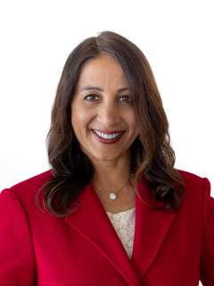 Dr. Nimmi Kappor smiling in red blazer headshot on white background