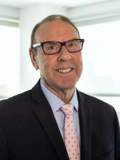 Dr. Michael Gottlieb, a smiling man in a dark suit with a light blue shirt and a pink polka-dot tie. He appears experienced and approachable.