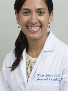 Kristin Schwab, MD, in a white coat, with a neutral background.