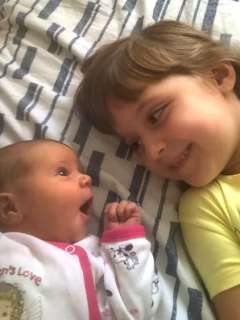 Ada Bogdan laying next to her newborn sister, Daria