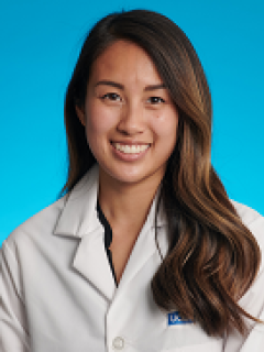 headshot of Emerly Luong, MD with white labcoat in front of a blue background