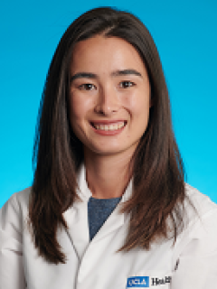A headshot of Erica Parker, MD wearing a white lab coat, with long brown hair and smiling. 