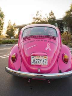 Rear view of the pink VW Beetle. Pink ribbons are visible on the trunk