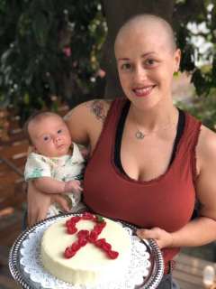 Christelle Jorda holding her 2 month old daughter and a cake