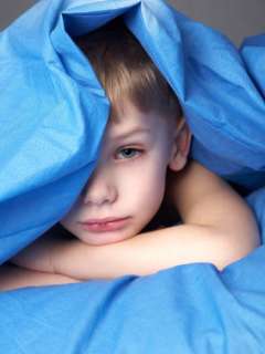 Boy laying under blue blanket