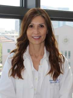 Portrait of Aksone Nouvong, DPM, in a white coat with a blurred face.