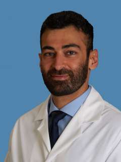 Person in white coat and tie against blue background