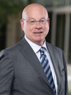 Dr. Michael Steinberg, wearing glasses and a dark suit with striped tie, smiling in a professional headshot.