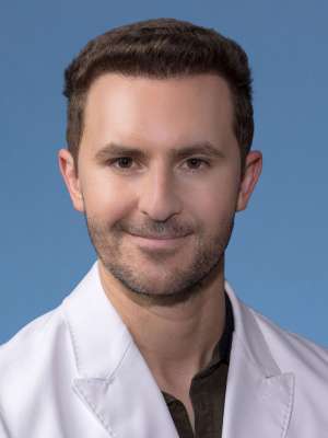 Joseph Giessinger, DO, MS in a white lab coat