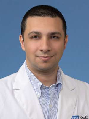 Head shot of Yousaf Ajam in white lab coat, smiling at camera