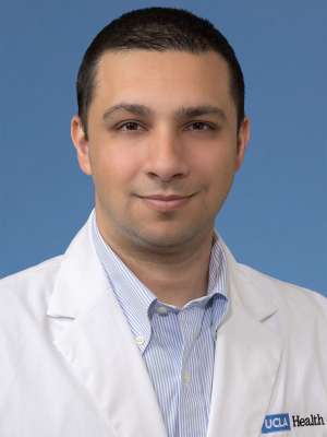 Head shot of Yousaf Ajam in white lab coat, smiling at camera