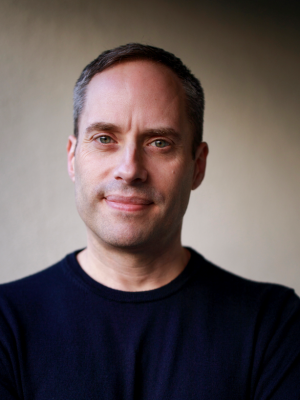 Person wearing a dark sweater against a neutral background