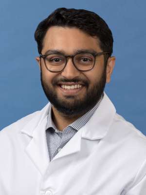 White coat head shot of Jason Gandhi, smiling at the camera