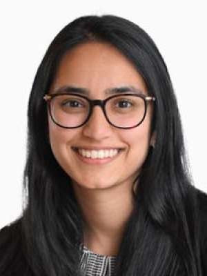 Smiling woman in glasses and dark blazer against white background