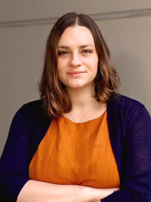 Headshot of Tara TeSlas in orange shirt and black cardigan