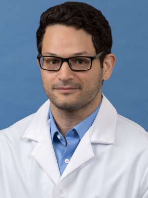 White coat head shot of Cameron Sarabi, giving a small smile at the camera