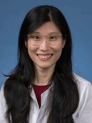 Head shot of Megan Cheng in white lab coat, smiling at camera