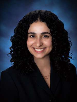 Head shot of Nicki Karimi-Mostowfi in a black suit jacket, smiling at the camera
