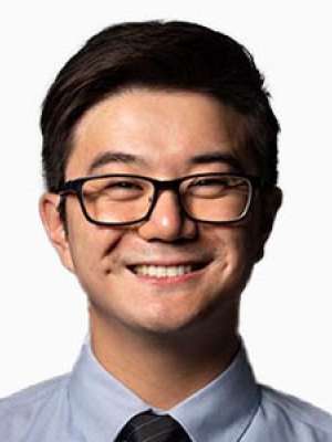 Smiling man wearing glasses, dress shirt, and tie headshot