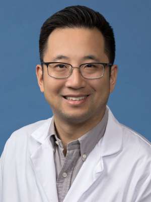 Alden Huang, PhD in a white lab coat