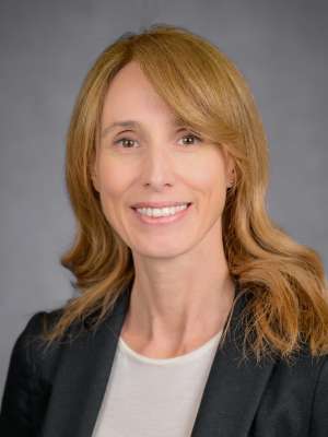 Smiling professional headshot of woman with light brown hair in black blazer
