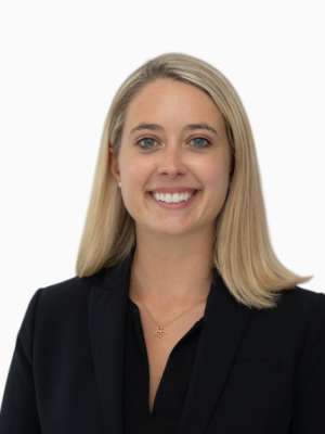 Smiling blonde woman headshot in black blazer on white background