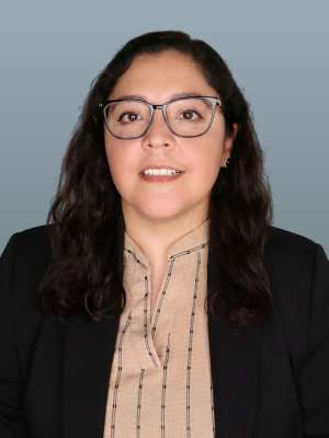 Head-and-shoulders portrait of woman with glasses wearing a blazer on gray background
