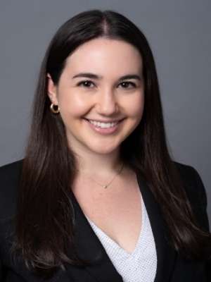 Professional headshot of woman with face obscured, long dark hair, black blazer.