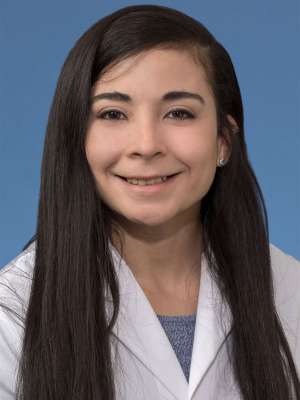 Head shot of Maria Garcia-Dominguez in white lab coat, smiling at camera