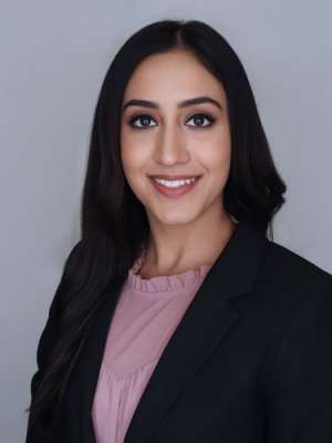 Headshot of Simrat in a black suit with pink shirt 