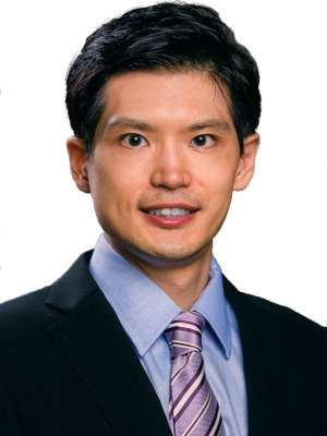Professional headshot: man in dark suit, light blue shirt, purple striped tie