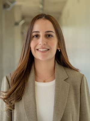 Smiling woman in beige blazer in a neutral hallway background