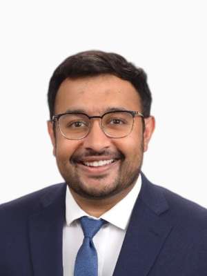 Nimish Garg smiling headshot wearing glasses, suit, and tie