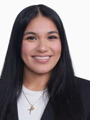 Nicole Kharoufa smiling headshot, dark hair, black blazer and white top.