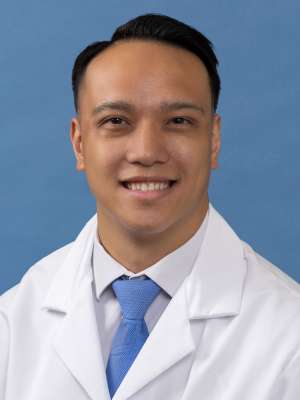 White coat head shot of Michael Arias, smiling at the camera