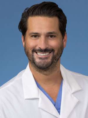 Head shot of Daniel Toro-Lira in white lab coat, smiling at camera