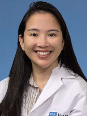 Head shot of Jaclyn Nguyen in white lab coat, smiling at camera
