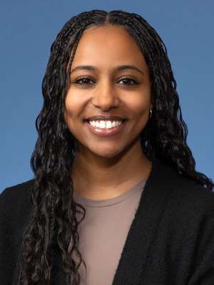 Woman with black cardigan and brown top.