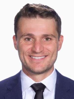 Caleb Irvine smiling headshot wearing a suit and tie