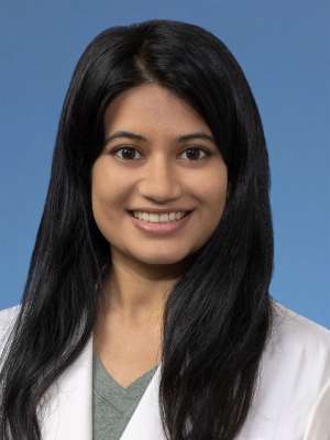 Head shot of Priyanka Deshpande, in white coat, smiling at camera