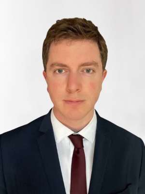 Head shot of Dylan Calame in business attire, looking at camera