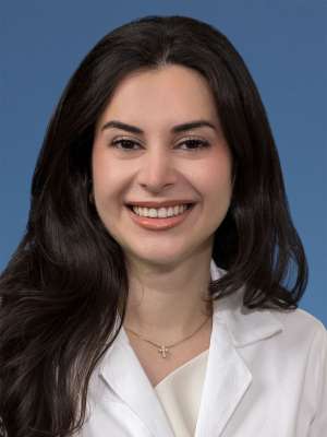 Head shot of Natalie Nabaty, MD in white coat, smiling at the camera