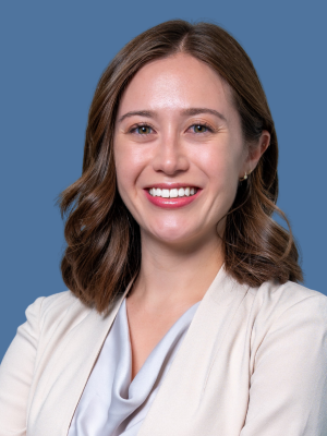 A caucasian woman smiling wearing a white blazer.