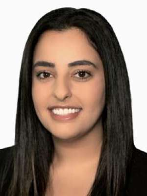 Headshot of Nikfar Shaya, smiling with dark hair and black blazer.