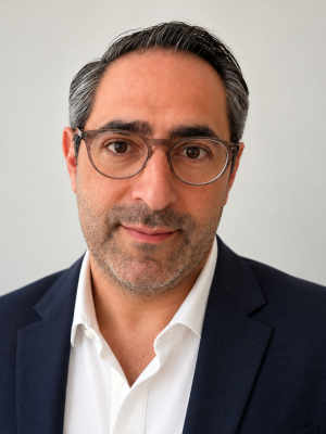Professional headshot of a man wearing glasses, navy blazer and white shirt.
