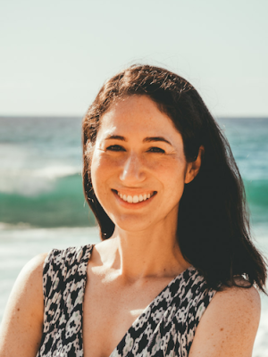 Smiling woman on a beach with waves behind her