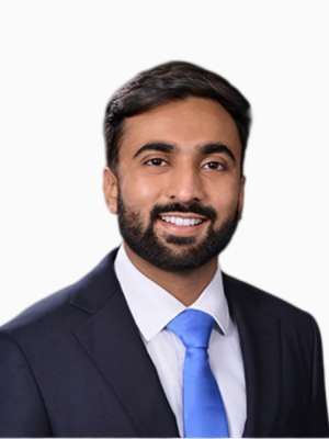Smiling man in dark suit and blue tie against white background.